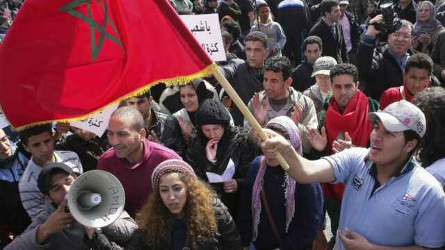 Protesters march during a protest and wave the Moroccan flag in Rabat, Morocco