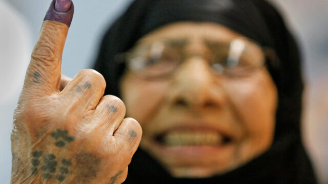 A woman holds up a finger with purple ink