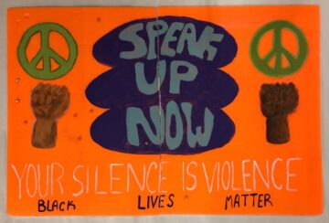 An orange poster that says Speak Up Now Your Silence is Violence